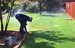 a League City sprinkler repair tech is checking a pop-up head